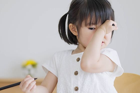 花を見て目をこする女の子