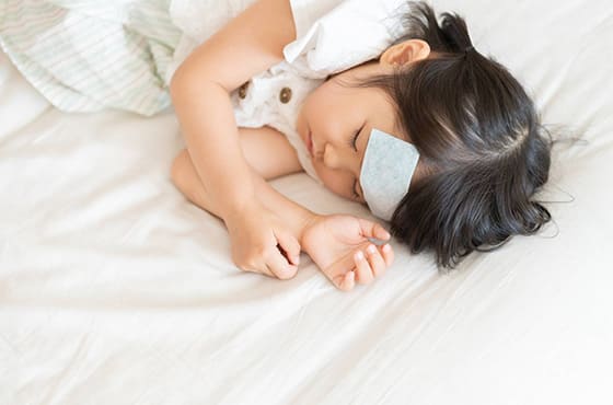 ひたいに熱冷ましをつけて眠る女の子