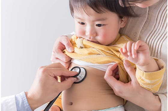 聴診器をお腹に当てられ診察を受ける子供